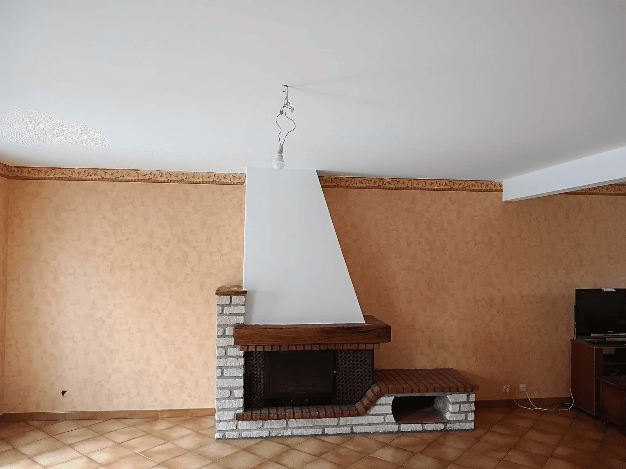 Séjour avec ancien papier peint orangé avant travaux de peinture